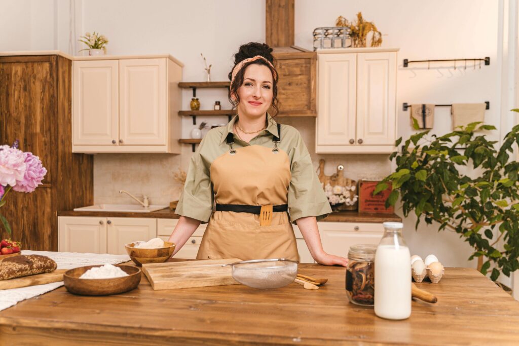 About Me 1 Confident woman standing in kitchen surrounded by baking ingredients