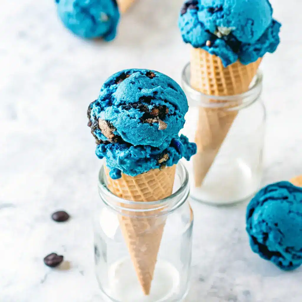Cookie Monster Ice Cream: A Fun, Flavorful Treat for All Ages 1 Blue Cookie Monster ice cream scooped into waffle cones placed in glass jars.
