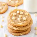 White Chocolate Chip Cookies – Soft, Chewy & Easy to Bake 5 Stack of soft white chocolate chip cookies with scattered white chips and a glass of milk in the background.