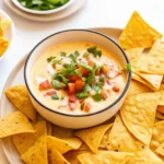 Cottage Cheese Queso: Creamy, High-Protein Dip You’ll Love 5 Creamy queso dip in a bowl surrounded by tortilla chips, topped with fresh herbs and tomatoes
