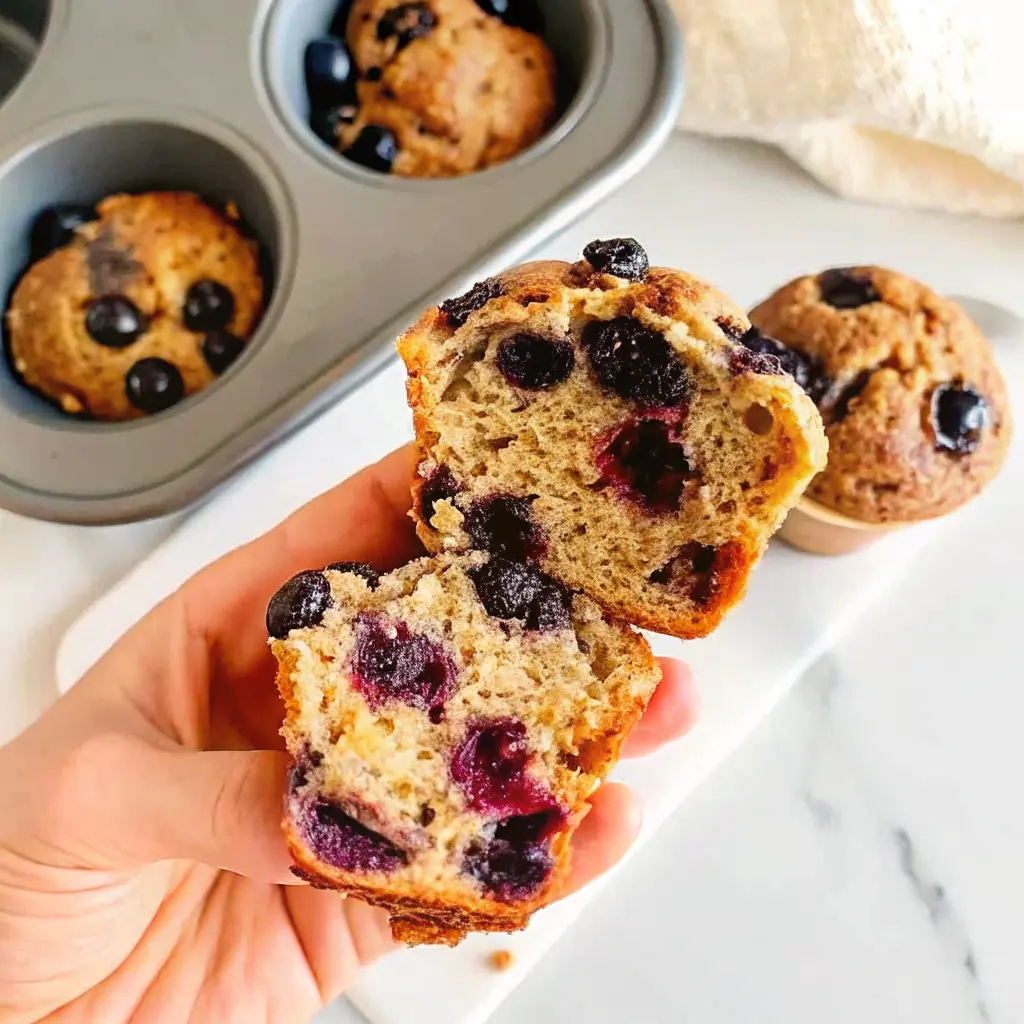 Cottage Cheese Blueberry Muffins: High-Protein, Easy, and Delicious 2 Hand holding halved muffin showing moist interior full of blueberries