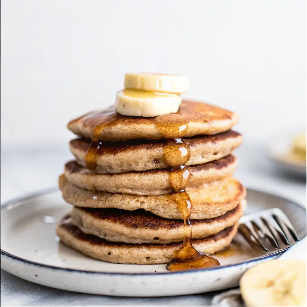 Banana Cottage Cheese Pancakes – Fluffy, Easy & High-Protein Breakfast 2 Thick banana cottage cheese pancakes stacked with syrup dripping and banana slices on top