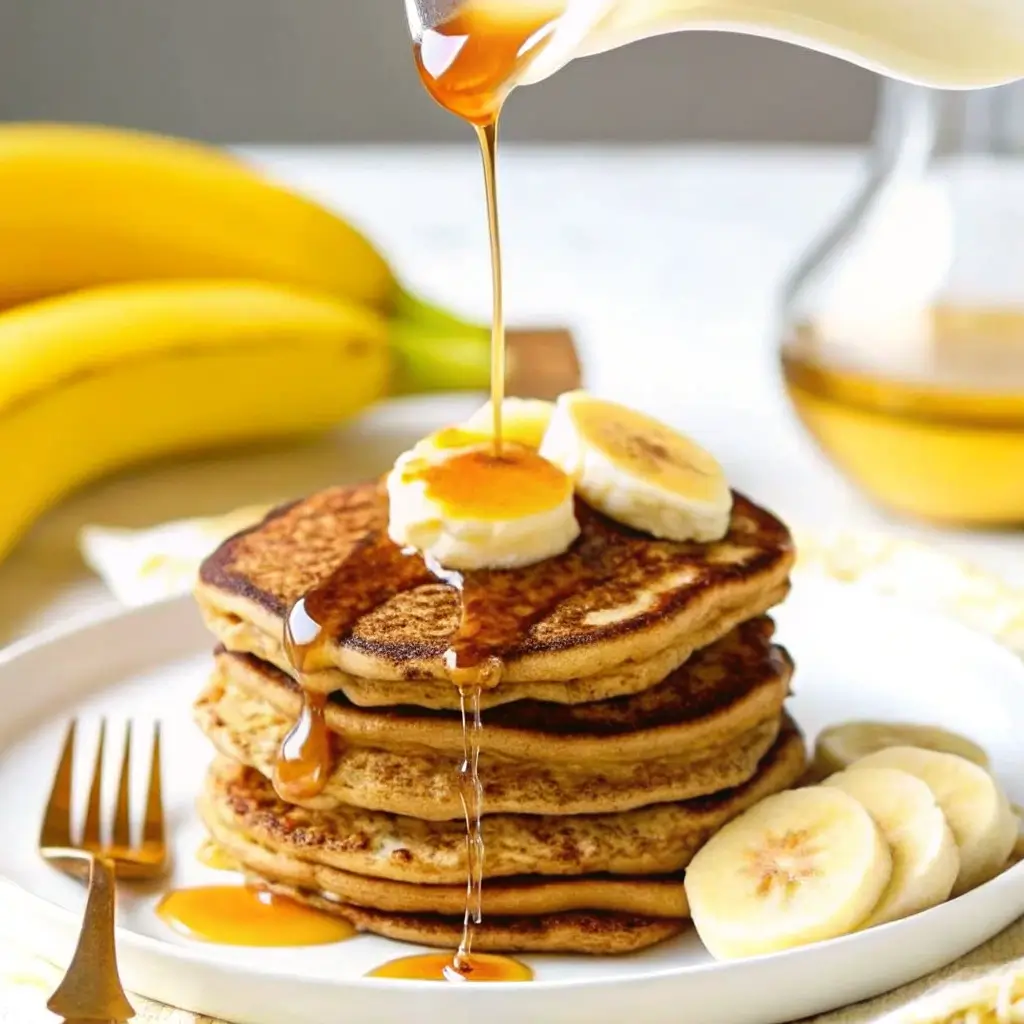 Banana Cottage Cheese Pancakes – Fluffy, Easy & High-Protein Breakfast 3 Syrup being poured over banana cottage cheese pancakes topped with banana slices