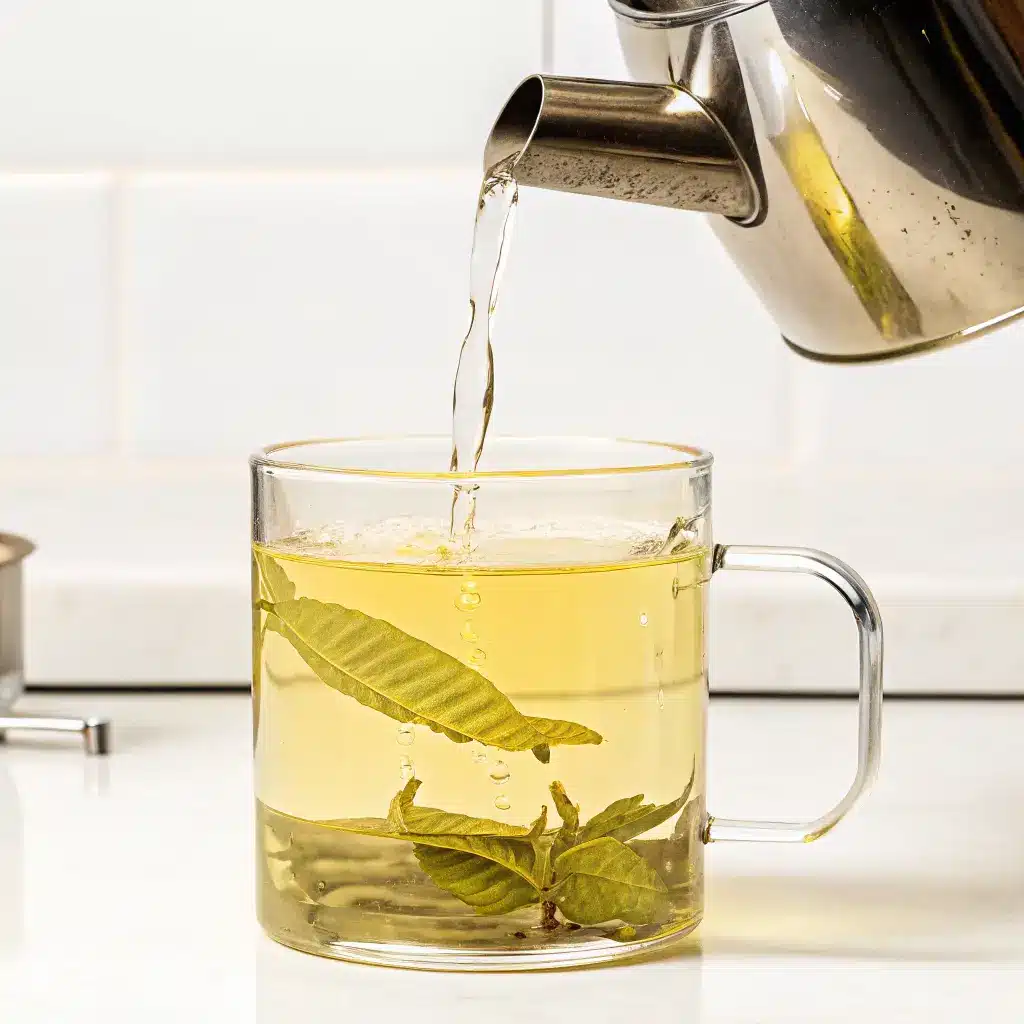 Lemon Verbena Tea Recipe: Soothing, Simple, and Full of Natural Benefits 4 Hot water being poured into glass cup of lemon verbena tea with leaves